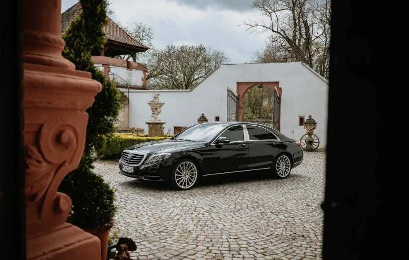 Schwarze Mercedes S-Klasse im gepflasterten Schlosshof