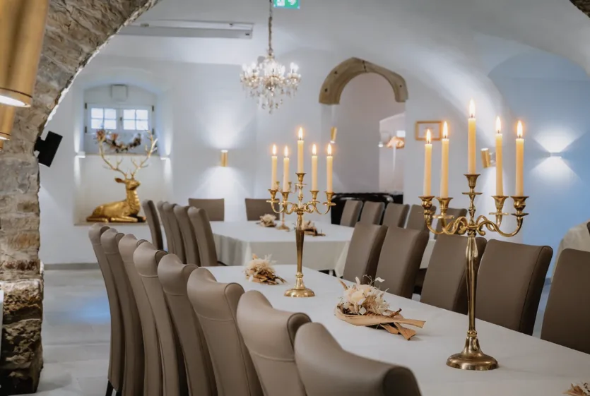 Festlich gedeckte Tafel im Festsaal mit goldenen Kerzenleuchtern und Trockenblumen